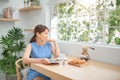 Happy young Asian woman using tablet and drink coffee in morning Royalty Free Stock Photo