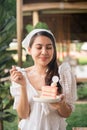 Happy young asian woman in white dress standing with deliciously eating a lychee cake Royalty Free Stock Photo