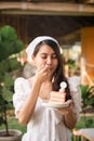 Happy young asian woman in white dress standing with deliciously eating a lychee cake Royalty Free Stock Photo