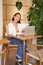 Happy young asian woman winning on laptop, receive good news, achieve goal at work, triumphing and smiling pleased Royalty Free Stock Photo