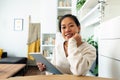 Happy young Asian woman working at home office holding tablet looking at camera. Royalty Free Stock Photo