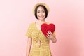 Happy young Asian woman in a yellow dress holding red hearts and smiling on pink background Royalty Free Stock Photo