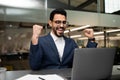 Happy young attractive arabic engineer businessman in glasses and suit rejoices to victory and great deal