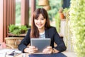 Happy young attractive business woman in her casual suit smiling at camera while working on her computer tablet at outdoor patio Royalty Free Stock Photo