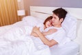 Happy young attractive couple hugging on bed in bedroom Royalty Free Stock Photo