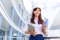 Happy young attractive female Asian engineer holding her computer tablet and blueprint while standing outside of office building Royalty Free Stock Photo