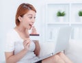 Happy young attractive woman shopping online via laptop computer, using credit card at home Royalty Free Stock Photo