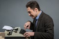 Happy young author typing at typewriter