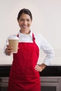 Happy young barista offering cup of coffee to go Royalty Free Stock Photo