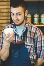 Happy young barista offering cup of coffee to go smiling at camera Royalty Free Stock Photo