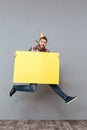 Happy young bearded birthday man holding copyspace board jumping