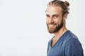 Happy young bearded guy with fashionable hairstyle and beard looking at camera, brightfully smiling with teeth, being