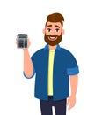 Happy young bearded man showing or holding a digital calculator device in his hand. Modern lifestyle, business and finance.