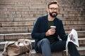 Happy young bearded man sitting outdoors on steps Royalty Free Stock Photo