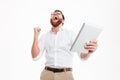 Happy young bearded man using tablet computer make winner gesture. Royalty Free Stock Photo