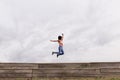 Happy young beautiful afro american woman listening to music in her mobile phone and jumping. Cloudy background. Spring or summer Royalty Free Stock Photo