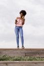 Happy young beautiful afro american woman smiling and talking on her mobile phone. cloudy background. Spring or summer season. Royalty Free Stock Photo