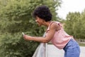 Happy young beautiful afro american woman smiling and using mobile phone. Green background. Spring or summer season. Casual Royalty Free Stock Photo