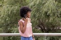 Happy young beautiful afro american woman smiling and using mobile phone. Green background. Spring or summer season. Casual Royalty Free Stock Photo