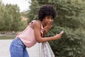 Happy young beautiful afro american woman smiling and using mobile phone. Green background. Spring or summer season. Casual Royalty Free Stock Photo