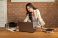 Happy young beautiful Asian businesswoman standing and looking at her laptop computer Royalty Free Stock Photo