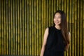 Happy young beautiful Asian businesswoman thinking against bamboo fence Royalty Free Stock Photo