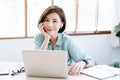 Happy young beautiful Asian Freelancer woman using laptop  computer and wireless earbuds working remote at home.She communicating Royalty Free Stock Photo