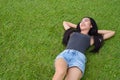 Happy young beautiful Asian woman laying down on grass at the park Royalty Free Stock Photo