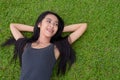 Happy young beautiful Asian woman laying down on grass at the park Royalty Free Stock Photo