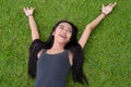 Happy young beautiful Asian woman laying down on grass at the park Royalty Free Stock Photo