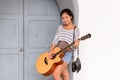 Happy young beautiful Asian woman playing guitar outdoors Royalty Free Stock Photo