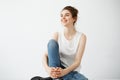 Happy young beautiful brunette girl with bun smiling laughing sitting over white background. Royalty Free Stock Photo