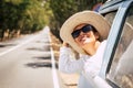 Happy young beautiful caucasian people female enjoy the sun outside the window of blue old vehicle - long road in background for