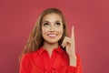 Happy young beautiful cheerful woman pointing up on colorful pink background portrait. Student girl pointing finger and looking up