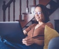 Happy young beautiful girl student in glasses works at a laptop at home, remote job and education Royalty Free Stock Photo