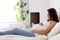 Happy young beautiful pregnant woman, sitting on bed in bedroom Royalty Free Stock Photo