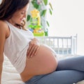 Happy young beautiful pregnant woman, sitting on bed in bedroom Royalty Free Stock Photo