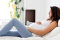 Happy young beautiful pregnant woman, sitting on bed in bedroom Royalty Free Stock Photo