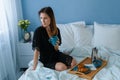 Happy young beautiful woman in bed with wooden tray with tasty breackfast at morning