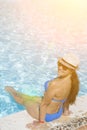 Happy, young beautiful woman in bikini sitting on edge of swimming pool, outdoors. Beautiful girl with relaxing near the Royalty Free Stock Photo