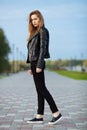 Happy young beautiful woman in black leather jacket black jeans slip-on posing for model tests in the summer park Royalty Free Stock Photo