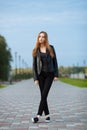 Happy young beautiful woman in black leather jacket black jeans slip-on posing for model tests in the summer park Royalty Free Stock Photo