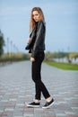 Happy young beautiful woman in black leather jacket black jeans slip-on posing for model tests in the summer park Royalty Free Stock Photo