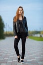 Happy young beautiful woman in black leather jacket black jeans slip-on posing for model tests in the summer park Royalty Free Stock Photo