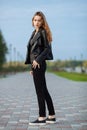 Happy young beautiful woman in black leather jacket black jeans slip-on posing for model tests in the summer park Royalty Free Stock Photo