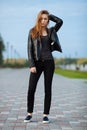 Happy young beautiful woman in black leather jacket black jeans slip-on posing for model tests in the summer park Royalty Free Stock Photo