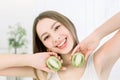 Happy young beautiful woman holding slices of kiwi fruit near her face - isolated on light background Royalty Free Stock Photo