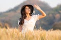 Happy young beautiful woman wearing black hat and white dress holding up her hand to block to sun shining on her face while Royalty Free Stock Photo