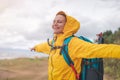 happy young beautiful woman in yellow jacket windbreaker with a hiking backpack on the shore of the North Sea