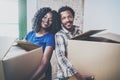 Happy young black african man and his girlfriend moving boxes into new house together and making a successful life